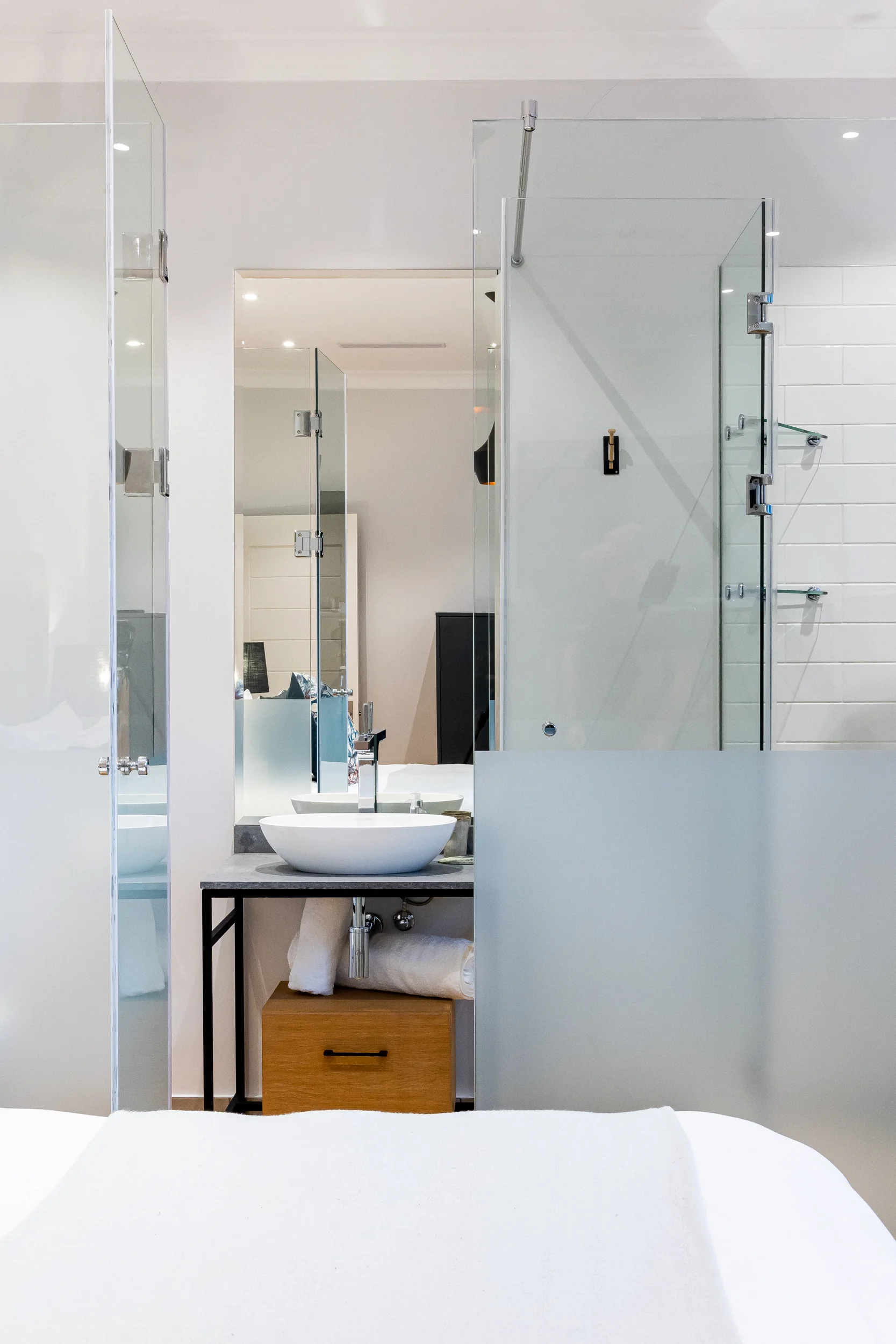 A bedroom at Rozenhof opening through glass to its en-suite basin and shower
