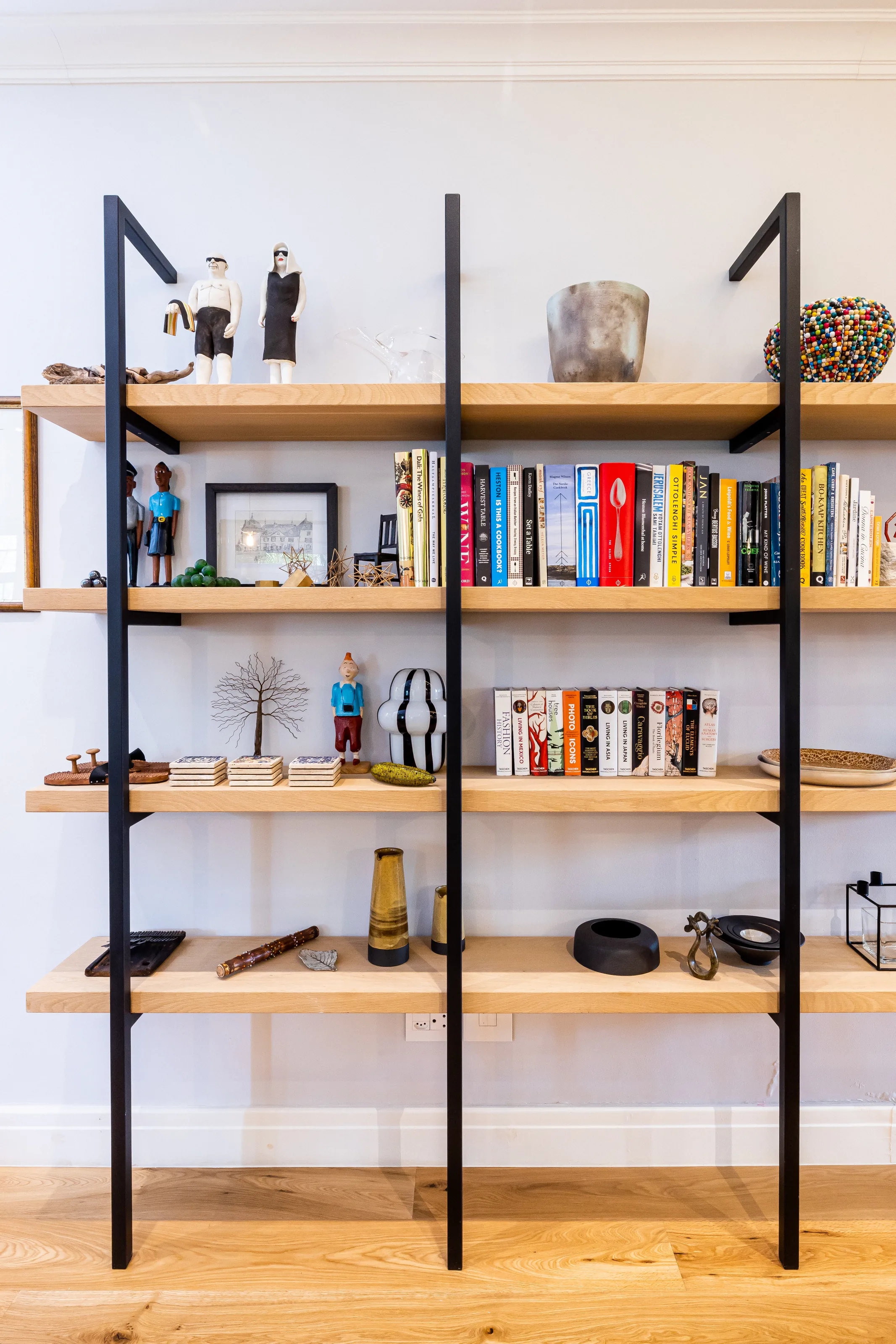 The oak and steel shelves at Rozenhof, filled with cookbooks, ceramics and carved figures